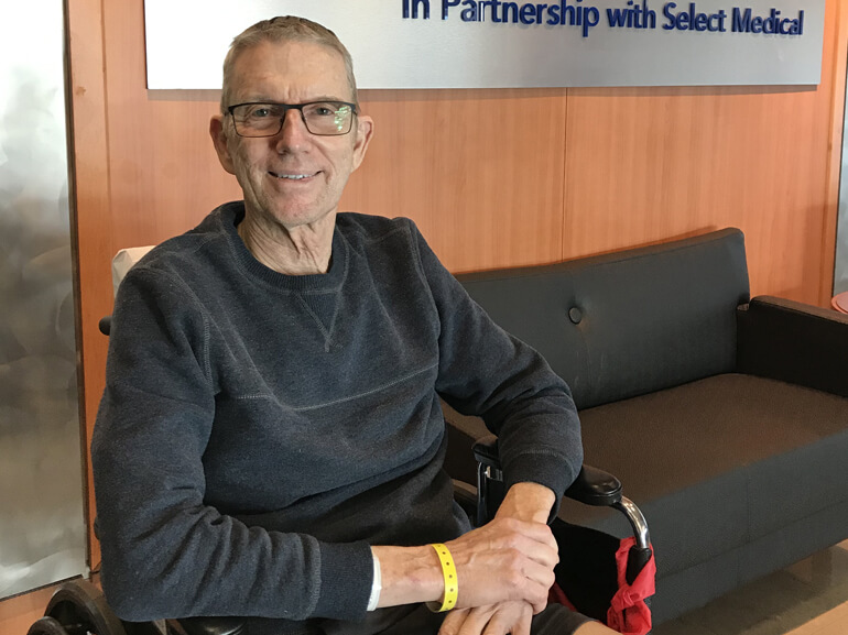 David sitting in a wheelchair in the hospital lobby before discharge to home.