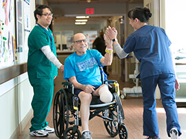 Male patient with below the knee amputation in wheelchair giving a high-five to a therapist.