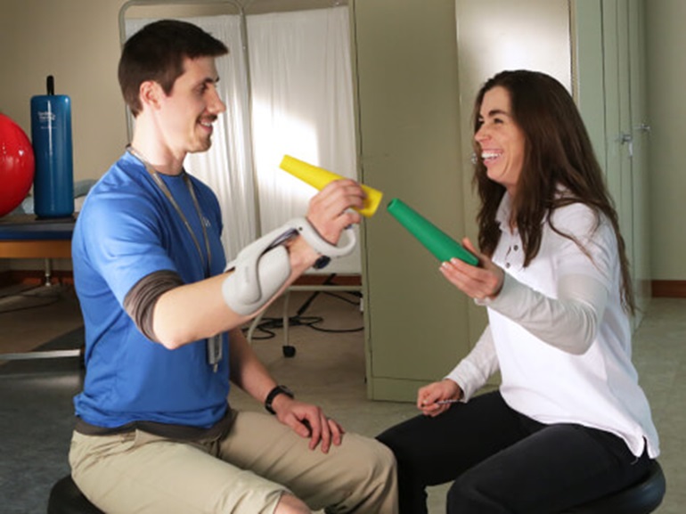 Male patient in blue shirt stacking yellow tube onto green tube.