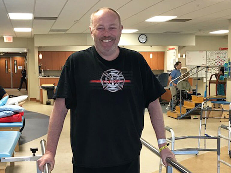 Charles using paralell bars in the gym for walking therapy.