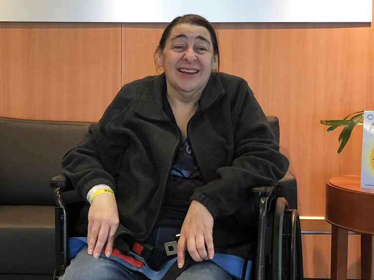 Kim in a wheelchair in the hospital lobby ready for discharge to home.