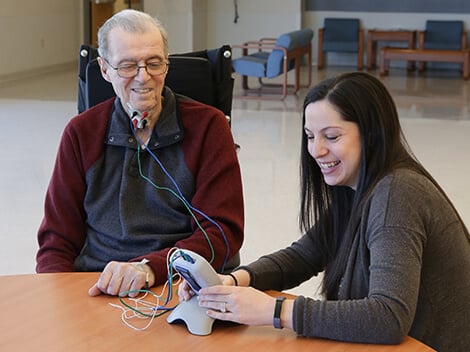 Senior male with small cords attached on his neck to stimulate his swallowing muscles.