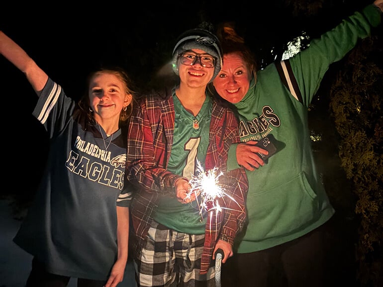Leo Hernandez holds a sparkler while standing between his mother and little sister.